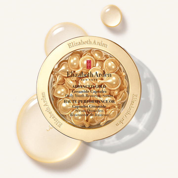 Elizabeth Arden Advanced Gold Ceramide Capsules in a round gold jar, shown open with golden capsules visible inside and additional translucent capsules floating around it on a light background.