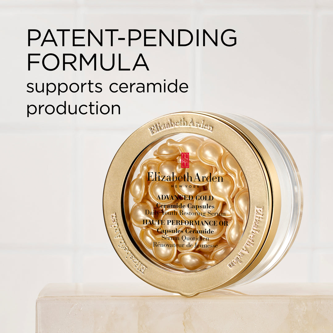 Elizabeth Arden Advanced Gold Ceramide Capsules jar with gold-toned capsules visible through the lid, set on a light marble surface against a white tiled background with promotional text.