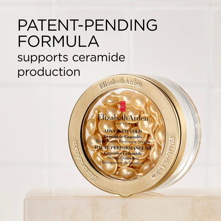 Elizabeth Arden Advanced Gold Ceramide Capsules jar with gold-toned capsules visible through the lid, set on a light marble surface against a white tiled background with promotional text.