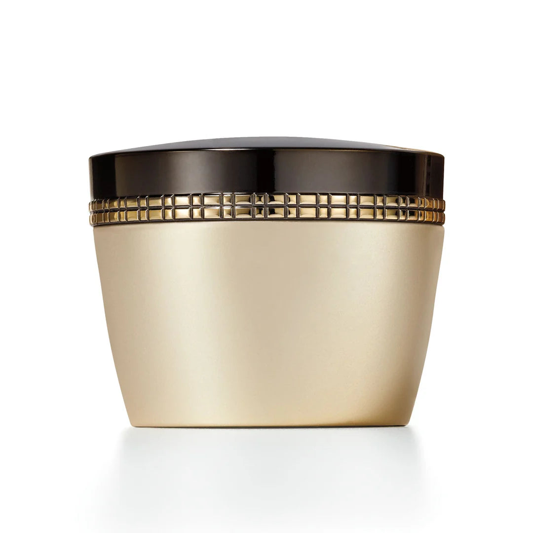 A cosmetic cream jar with a metallic gold body and a glossy black lid, featuring a decorative gold grid pattern band around the middle, set against a plain white background.