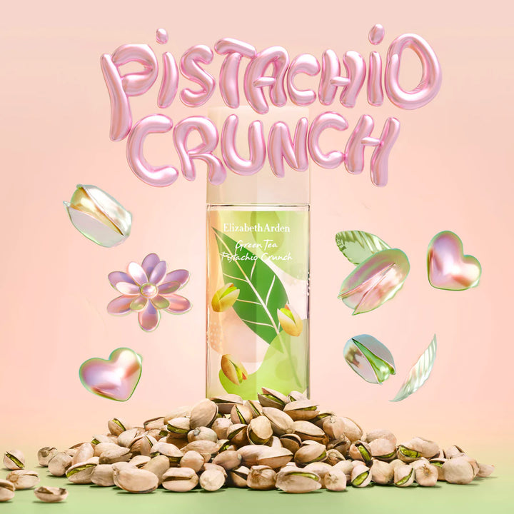 A bottle of Elizabeth Arden Pistachio Crunch moisturizing cream stands upright on a pile of shelled pistachios, with large pink balloon-style text reading 'Pistachio Crunch' above and floating iridescent pistachio and leaf graphics on a soft peach background.