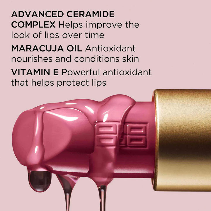 Pink lip balm with gold cap on a pink background, featuring text about its ingredients.