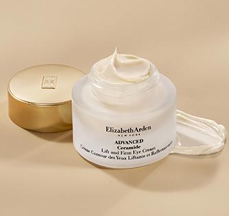 Elizabeth Arden Advanced Ceramide Lift and Firm Eye Cream in a frosted white jar with a gold lid, shown next to a smear of the white cream on a warm beige background.
