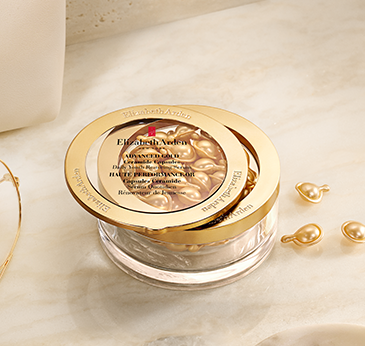 Elizabeth Arman multi-hydration cream jar with a gold lid, shown on a light marble surface with gold capsules nearby.