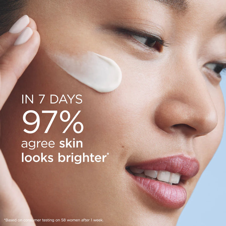 Close-up of a woman's face with a smear of white cream on her cheek and large marketing text reading 'IN 7 DAYS 97% agree skin looks brighter' over a light blue background.