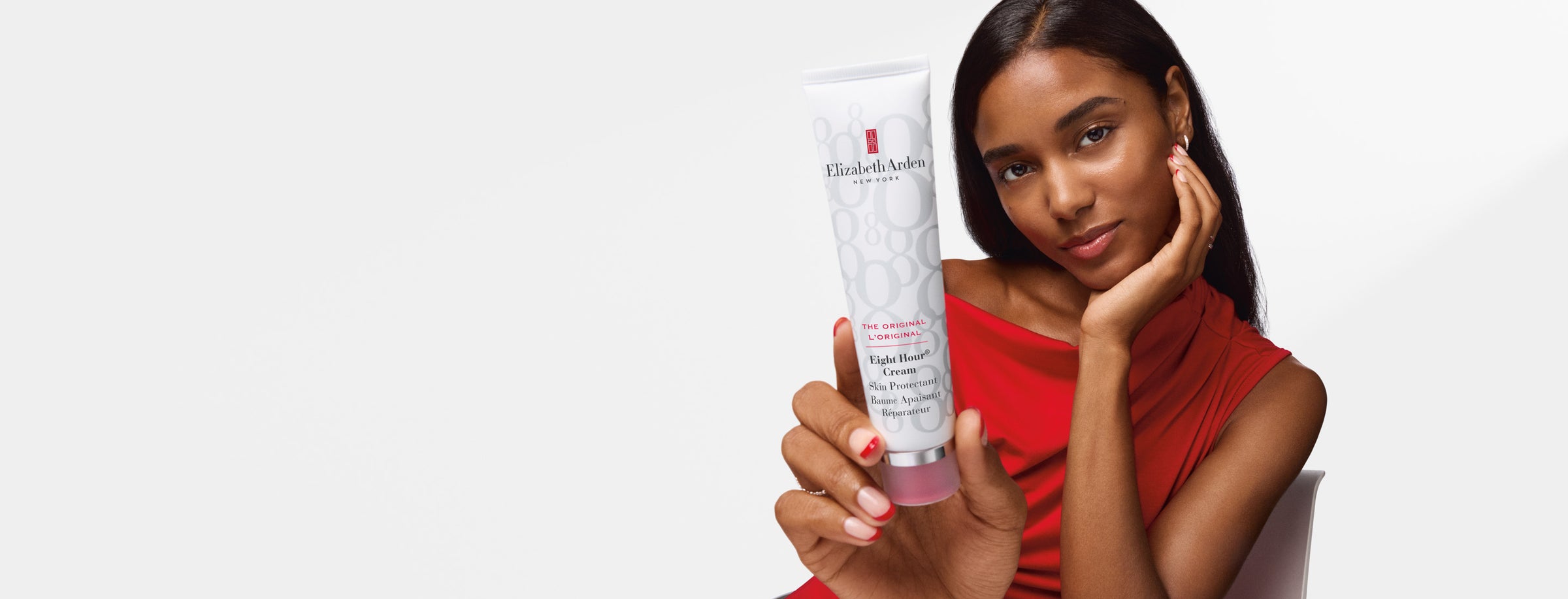 A woman in a red top holds up a white tube of Elizabeth Armand Paris Purifying Gel on a clean white background.