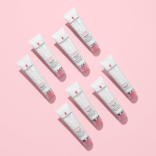 Six white skincare tubes with pink caps arranged diagonally on a solid pink background. The tubes feature the Elizabeth Armand logo and text for 'Soleil de Nuit Crèche' in black and red print.
