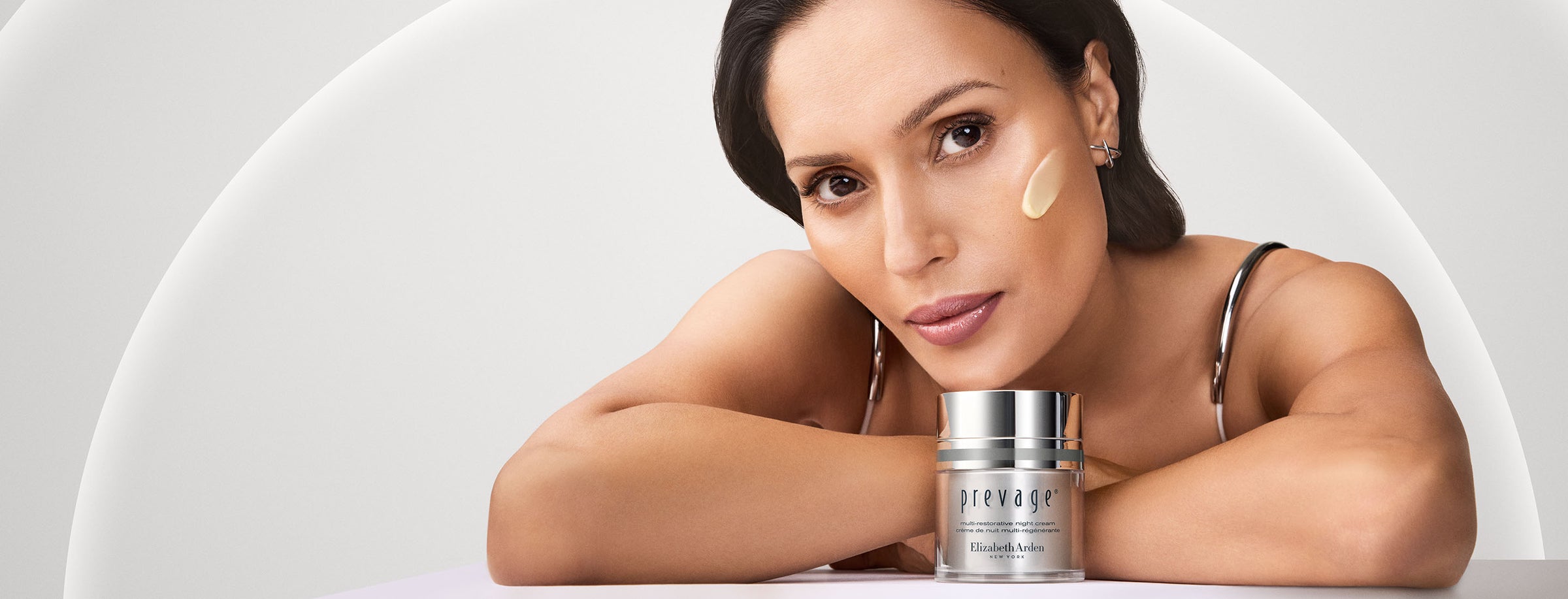 Model with Prevage cream in front of her on a grey background - Desktop Size