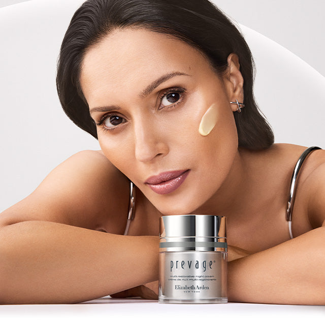Model with Prevage cream in front of her on a grey background - Mobile Size